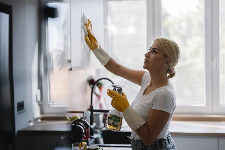 Femme qui nettoie des placards de cuisine